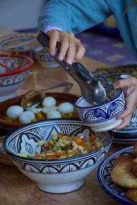 a person pouring a spoon into a bowl of food at Berber Waves Surf House in Tamraght Ouzdar