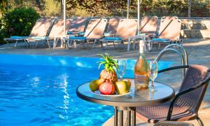a table with fruit and a bottle of wine next to a pool at Plaisir Beachside Apts in Agios Nikolaos