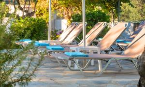 a row of lounge chairs sitting on a patio at Plaisir Beachside Apts in Agios Nikolaos