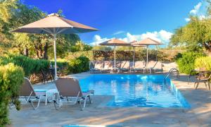 a swimming pool with lounge chairs and umbrellas at Plaisir Beachside Apts in Agios Nikolaos