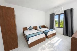 a bedroom with two beds and a window at Đức Lưu Quang Hotel Bình Thuận in Tuy Phong