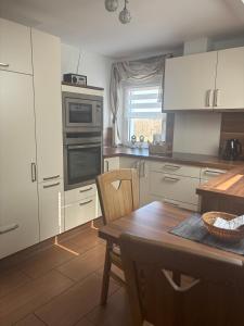 a kitchen with white cabinets and a wooden table at Ferienwohnung Schaller in Berg