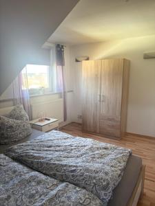 a bedroom with a large bed and a wooden cabinet at Ferienwohnung Schaller in Berg