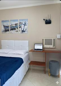 a bedroom with a bed and a desk with a laptop at Linda casa em Tarituba in Paraty