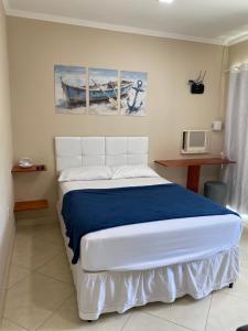 a bedroom with a white bed with a blue blanket at Linda casa em Tarituba in Paraty