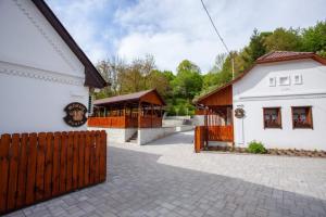 a white building with a fence next to a house at Nagyon Vadon vendégház in Háromhuta