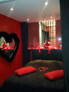 1 dormitorio con 1 cama con paredes rojas y espejo en La Cage Village Naturiste, en Cap d'Agde