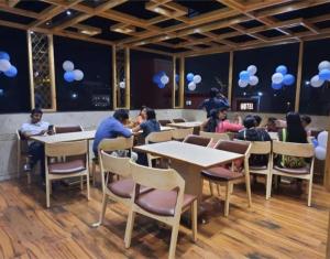 a group of people sitting at tables in a restaurant at Hotel Royal Treat Surat in Surat