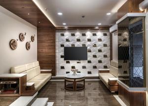 a living room with a couch and a tv at Hotel Royal Treat Surat in Surat