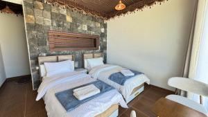 two beds in a room with a stone wall at Al khitaym guest house in Sa‘ab Banī Khamīs