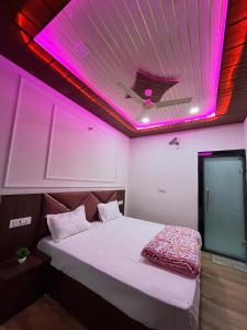 a bedroom with a bed with a pink lighting at Hotel Raghav in Orchha +10 photos