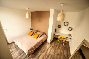 a bedroom with a bed and a desk with a yellow chair at Le Millésime in Chalons en Champagne