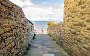 a stone wall with a pathway next to the ocean at Longshore Drift in Woodhorn