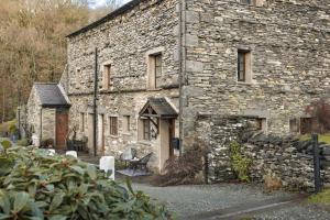 an old stone building with chairs in front of it at 1 Force Mill Barn - Ridgestone in Ulverston
