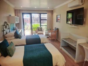 a hotel room with two beds and a television at The Ranch Guesthouse in Potchefstroom