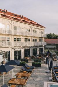 a hotel with lounge chairs and umbrellas in a courtyard at Kusthotellet Styrsö in Styrsö