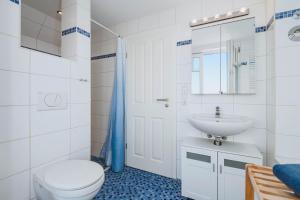 a white bathroom with a toilet and a sink at Strandgut in Börgerende-Rethwisch +34 photos