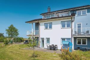 a large white house with chairs and a yard at Strandgut in Börgerende-Rethwisch