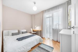 a white bedroom with a large bed and a desk at Modern old town apartment in Bratislava