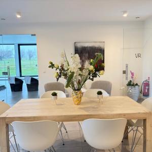 a dining room table with a vase of flowers on it at Vita Roka met extra Luxe Privé Wellness in Ursel