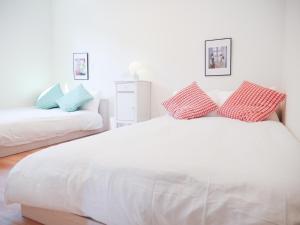 a white bed with red and blue pillows on it at 9Stay伊勢崎 in Isesaki