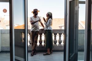 a man and woman standing on a balcony looking at their cell phones at Stay Hotel Lisboa Centro Chiado in Lisbon