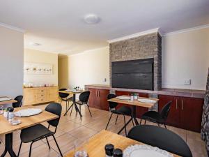 a dining room with tables and chairs and a flat screen tv at Olive Grove Bed & Breakfast in Kraaifontein