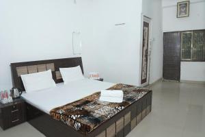 a bedroom with a large bed with white sheets at Omji Ashram Jageshwar Mahadev in Varanasi +2 photos
