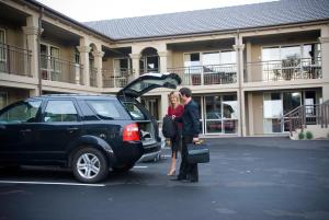 een man en vrouw die naast een auto staan met de kofferbak open bij Salerno Motel Apartments in Christchurch