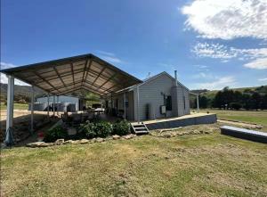 a house with a large roof on a field at BrinCole - Pet-Friendly, Huge Deck with Epic Views & Fire Pit in Bonnie Doon