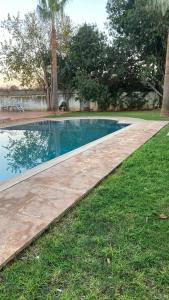 a swimming pool with a walkway next to a yard at Big Villa In Rabat in Rabat