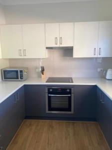 a kitchen with white cabinets and a black oven at BrinCole - Pet-Friendly, Huge Deck with Epic Views & Fire Pit in Bonnie Doon +10 photos