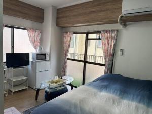 a bedroom with a bed and a tv and a window at Peace Wing 3C in Hiroshima