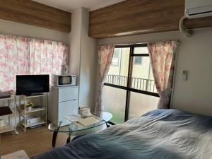 a bedroom with a bed and a table and a window at Peace Wing 3C in Hiroshima