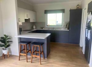 a kitchen with a white counter and two stools at BrinCole - Pet-Friendly, Huge Deck with Epic Views & Fire Pit in Bonnie Doon