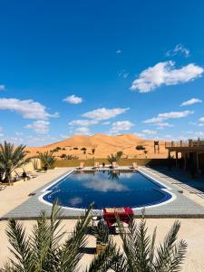 a swimming pool in the middle of the desert at Hotel Camping Les Roses Des Dunes & Piscine in Merzouga