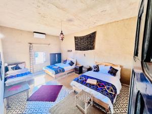 a room with two beds and a couch at Hotel Camping Les Roses Des Dunes & Piscine in Merzouga