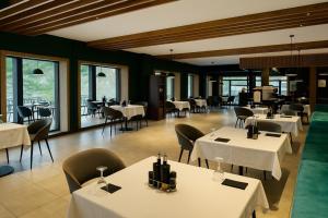 a restaurant with white tables and chairs and windows at LAKEVIEW Hotel & Apartments in Mavrovo