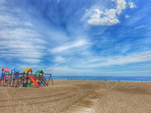 un parque infantil en una playa con el océano en el fondo en Apartamentos Doña Lucía, en Torremolinos