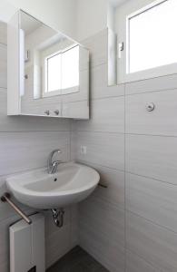 a white bathroom with a sink and a mirror at Ferienwohnung "Mour" in Dahme +10 photos