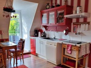 a kitchen with red and white cabinets and a table at Ferienwohnung Leuchtfeuer in Burhave