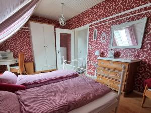 a bedroom with red wallpaper and a bed and a dresser at Ferienwohnung Leuchtfeuer in Burhave