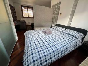 a bedroom with a bed with a blue and white plaid blanket at BASTIA RF Suite up to 4 guests - in the heart of Scalo Romana, Olimpico, Prada, Bocconi and easy access Forum Assago, IEO, IED, Duomo, San Siro in Milan