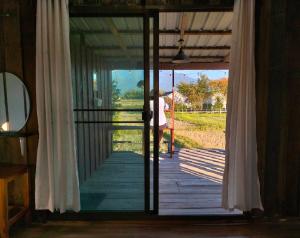 a door to a porch with a person standing outside at Ricefield Homestay มองนาภูคาน่านโฮมสเตย์ in Ban Thon (1)