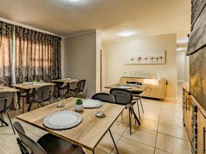 a dining room with tables and chairs and a kitchen at Olive Grove Bed & Breakfast in Kraaifontein