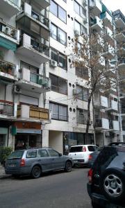 two cars parked in front of a tall building at Monoambiente cómodo in Buenos Aires