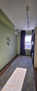 an empty living room with a large window and a rug at Koktem hostel in Aktobe