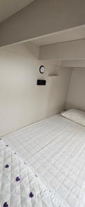 a white bed in a room with a clock on the wall at Koktem hostel in Aktobe