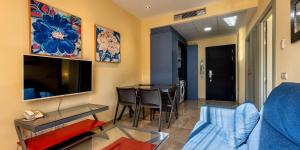 ein Wohnzimmer mit einem blauen Sofa und einem Tisch in der Unterkunft Apartamentos Vértice Sevilla Aljarafe in Bormujos