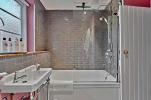 a bathroom with a white tub and a sink at Finest Retreats - Flittermouse Cottage in Wingfield